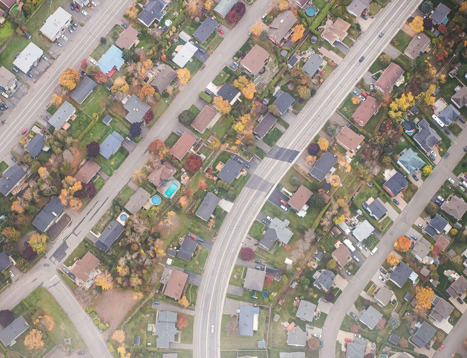 An aerial view of a suburban neighborhood in the fall, with winding streets and colorful trees